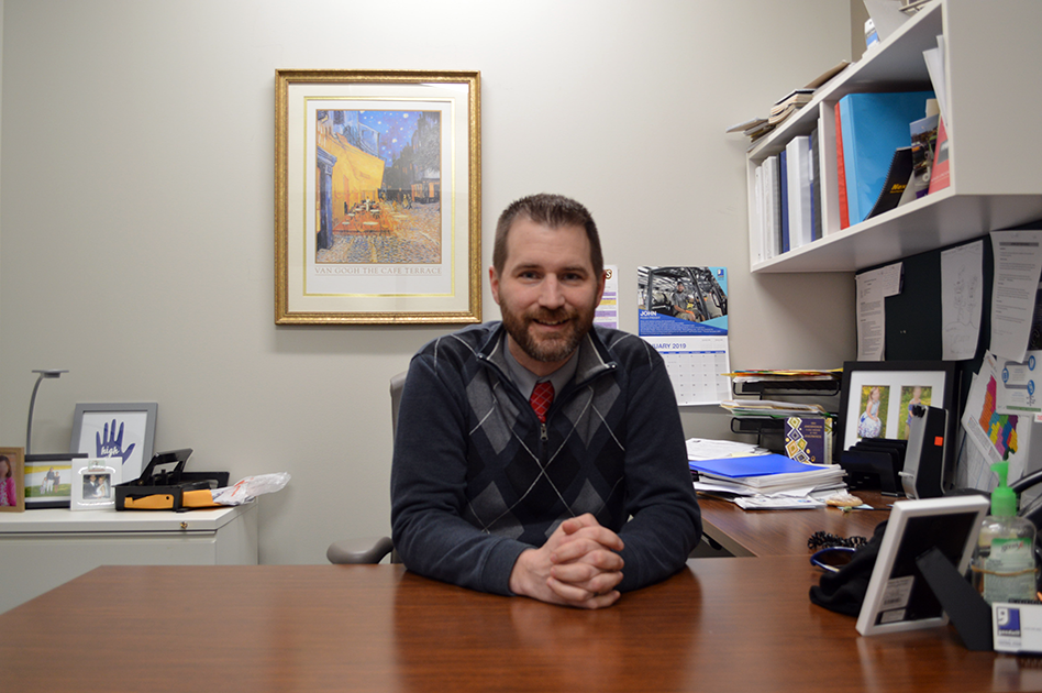 Justin poses at his desk.